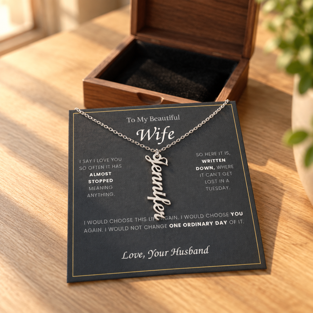 Name necklace and its message card on an oak table, beside the open wooden gift box