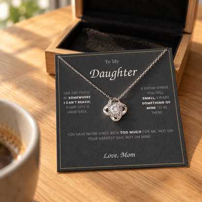 Love Knot necklace and its message card on an oak table in morning light