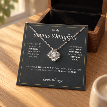 Love Knot necklace and its message card on an oak table beside the open wooden gift box