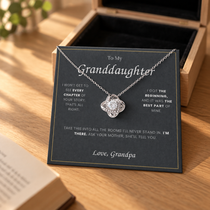 Love Knot necklace and its message card propped against the open gift box on an oak table