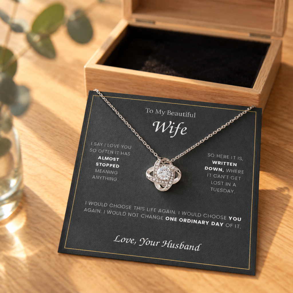 Love Knot necklace and its message card on an oak table beside the open wooden gift box